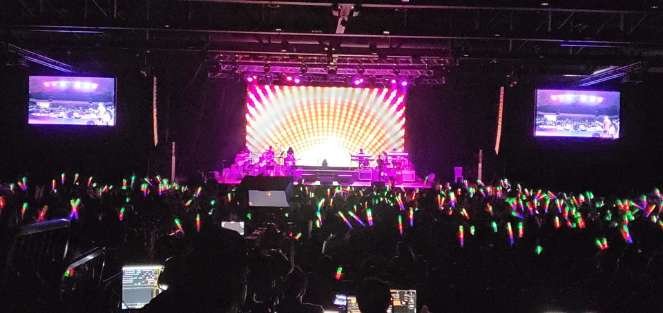 View across the audience toward the main display and side screens.